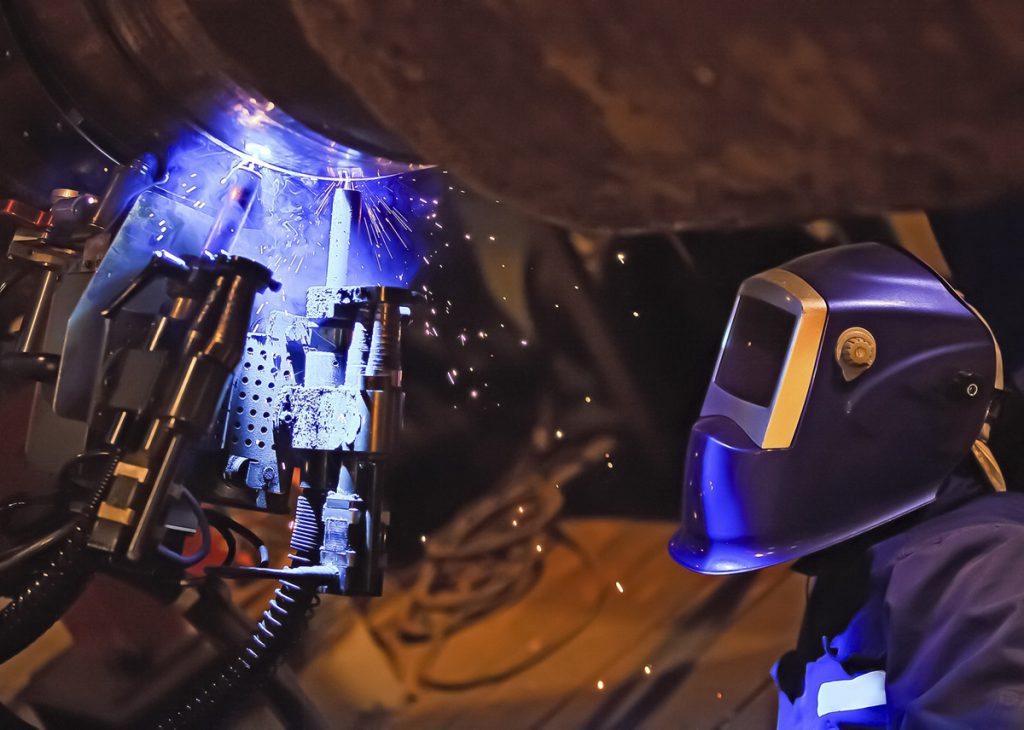 Operator welding a pipe with twin wire welding automation head